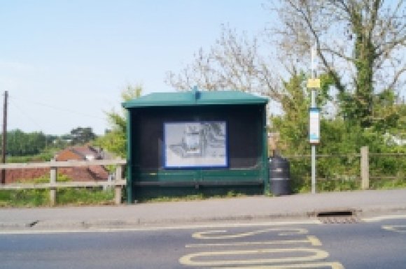 Picture of bus shelter Eastbound on Canterbury Road at the bottom of 'Wibbly Wobbly' hill with a Village Noticeboard inside the shelter.